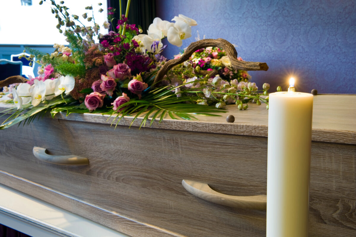 casket at memorial service with flowers and candle